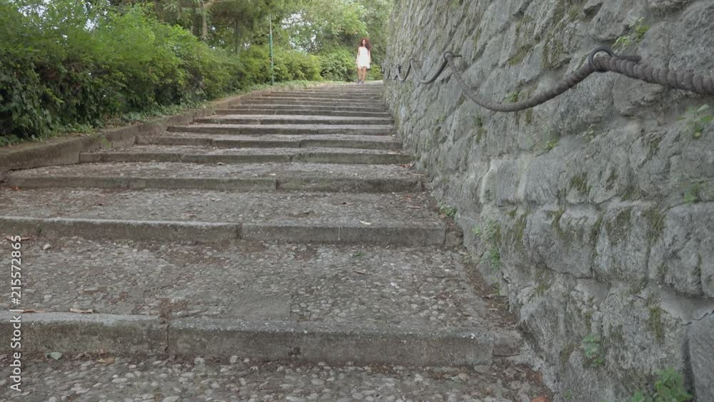 Mature woman descends from an old stone stairway Mature woman descends from an old stone stairway