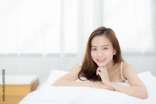 Beautiful portrait young asian woman lying and smile while wake up with sunrise at morning, lifestyle and relax concept.