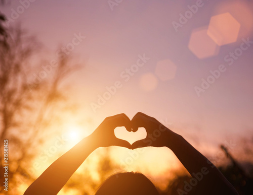 hands forming a shape with sunset silhouette