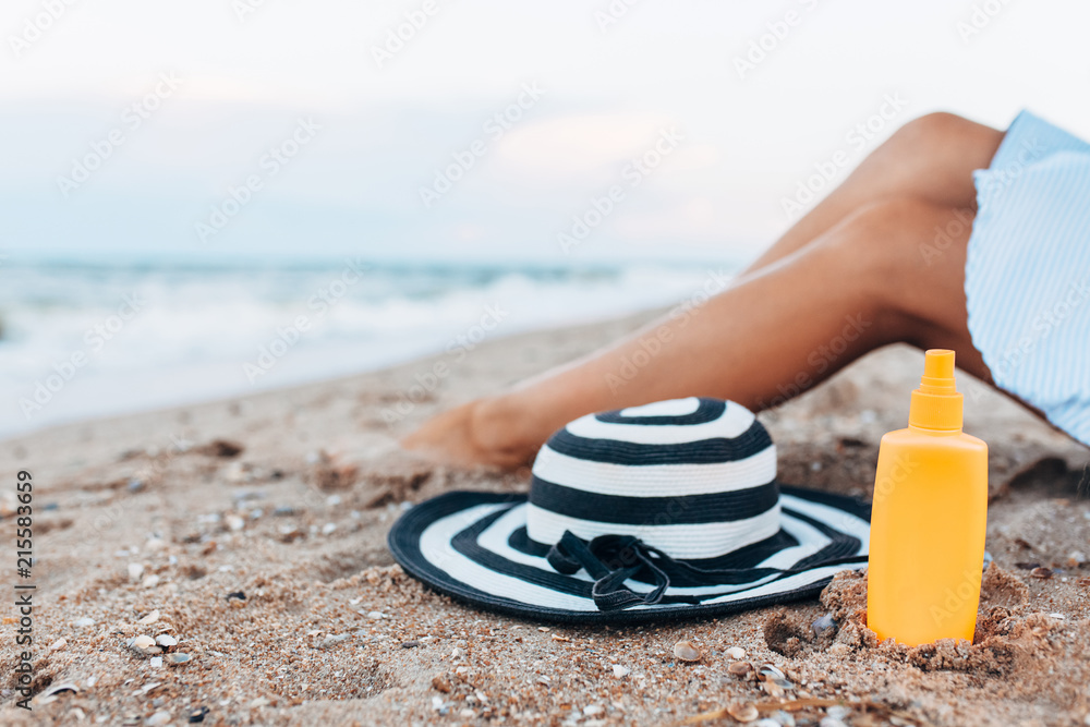 girl resting on the beach, beautiful tanned legs against the blue sea, jar of cream