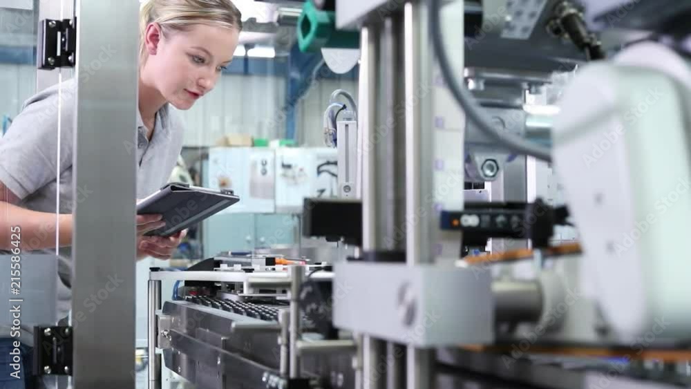 Female Engineer With Digital Tablet Checking Automated Machine In Factory Female Engineer With Digital Tablet Checking Automated Machine In Factory