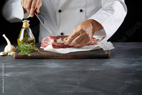 Chef cutting lamb chop with knife on cutting board
