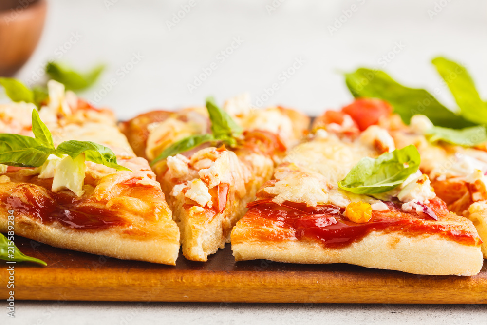 Oval homemade pizza with feta cheese, tomatoes and basil on a wooden board. Oval homemade pizza with feta cheese, tomatoes and basil on a wooden board.