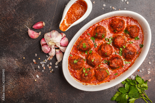 Meatballs in tomato sauce with parsley and garlic in white dish, top view, copy space.