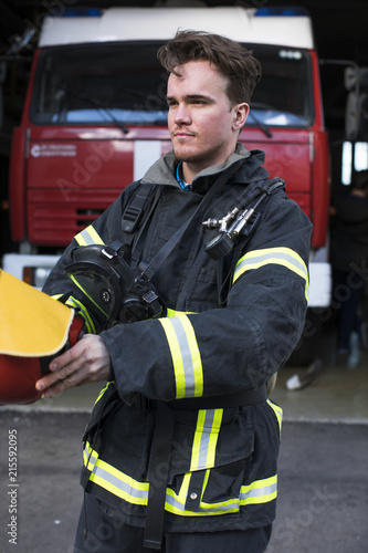 Portrait of a young fireman on the background of a fire truck