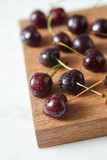Close-up ripe sweet cherry in water droplets on a wooden board on white background with soft focus.