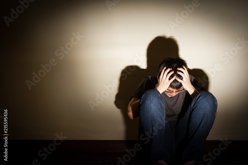 depressed despaired young man sit on the floor hiding his face