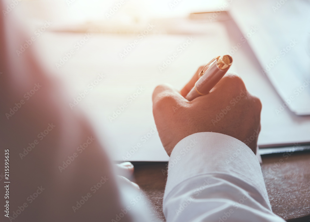 Businessman writing signed agreements on official documents to the company's profits. Which is filled with documents and concepts for the cooperation of its partners.