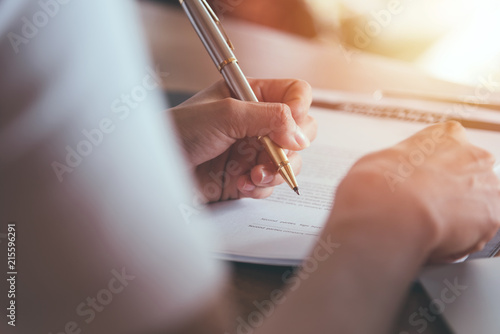 Businessman writing signed agreements on official documents to the company s profits. Which is filled with documents and concepts for the cooperation of its partners.