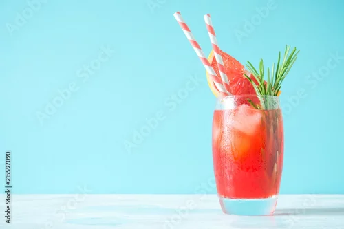Obraz Orzeźwiający koktajl grejpfrutowy z lodem i rozmarynem na kolorowym tle mięty. Zdrowy letni napój cytrusowy.