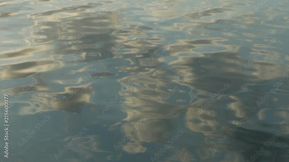 Slow motion of ripple on dark blue water surface with reflection of blue sky and white clouds. Slow motion of ripple on dark blue water surface with reflection of blue sky and white clouds.