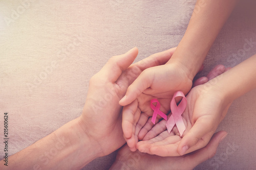 Adult and child hands holding pink ribbons, Breast cancer awareness, abdominal cancer awareness and October Pink, world cancer day