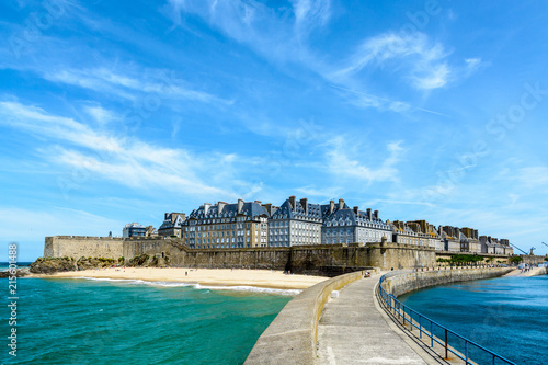 The walled city of Saint-Malo in Brittany, France, with granite residential buildings sticking out above the rampart and the Mole beach at the foot of the fortifications, seen from the breakwater.