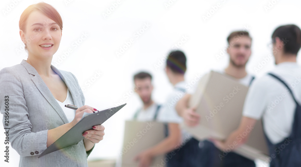 Woman manager holding clipboard on blurred background with mover Woman manager holding clipboard on blurred background with mover