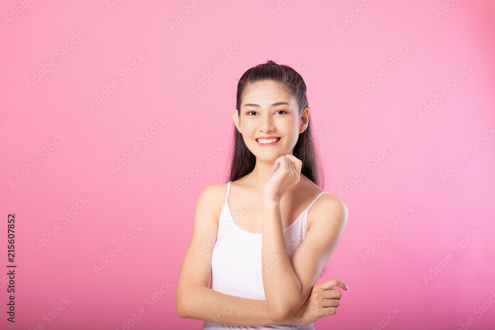 Portrait of a smiling attractive woman in white tanktop outfit posing while standing and smiling at camera isolated over pink background. Portrait of a smiling attractive woman in white tanktop outfit posing while standing and smiling at camera isolated over pink background.