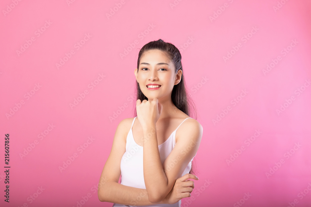 Portrait of a smiling attractive woman in white tanktop outfit with thinking pose while standing and smiling at camera isolated over pink background. Portrait of a smiling attractive woman in white tanktop outfit with thinking pose while standing and smiling at camera isolated over pink background.