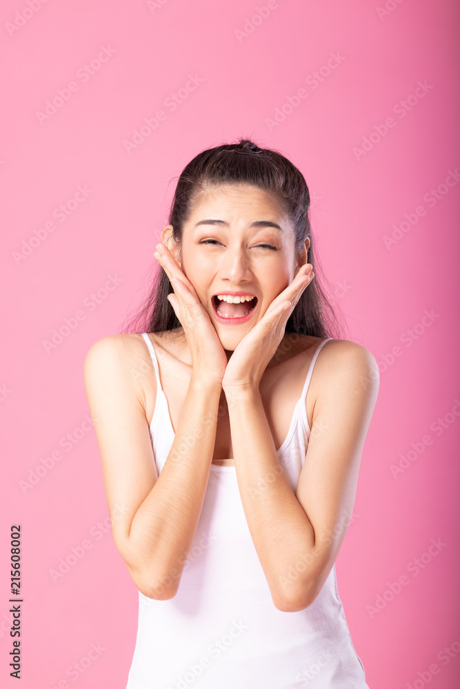 Portrait of a smiling attractive woman in white tanktop outfit with surprise pose while standing and smiling at camera isolated over pink background. Portrait of a smiling attractive woman in white tanktop outfit with surprise pose while standing and smiling at camera isolated over pink background.
