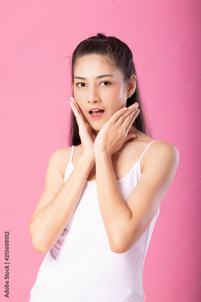 Portrait of a smiling attractive woman in white tanktop outfit with surprise pose while standing and smiling at camera isolated over pink background. Portrait of a smiling attractive woman in white tanktop outfit with surprise pose while standing and smiling at camera isolated over pink background.