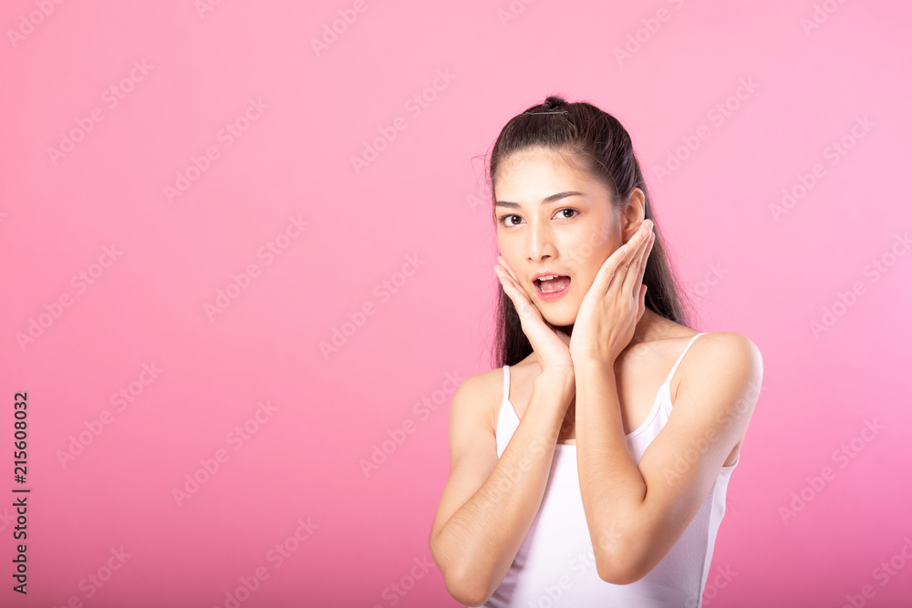 Portrait of a smiling attractive woman in white tanktop outfit with surprise pose while standing and smiling at camera isolated over pink background. Portrait of a smiling attractive woman in white tanktop outfit with surprise pose while standing and smiling at camera isolated over pink background.