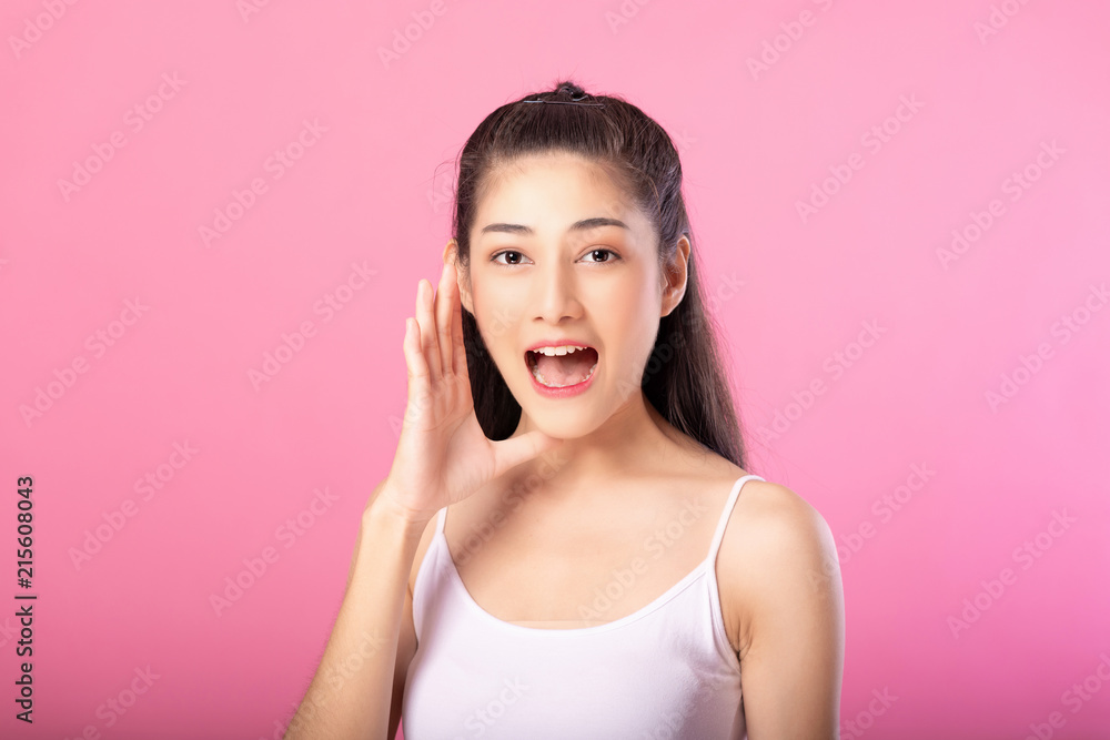 Portrait of a smiling attractive woman in white tanktop outfit with shouting pose while standing and smiling at camera isolated over pink background. Portrait of a smiling attractive woman in white tanktop outfit with shouting pose while standing and smiling at camera isolated over pink background.