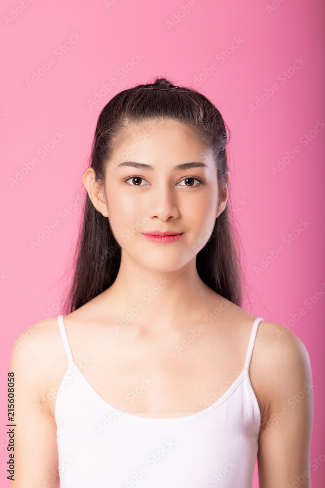 Portrait of a smiling attractive woman in white tanktop outfit posing while standing and smiling at camera isolated over pink background. Portrait of a smiling attractive woman in white tanktop outfit posing while standing and smiling at camera isolated over pink background.