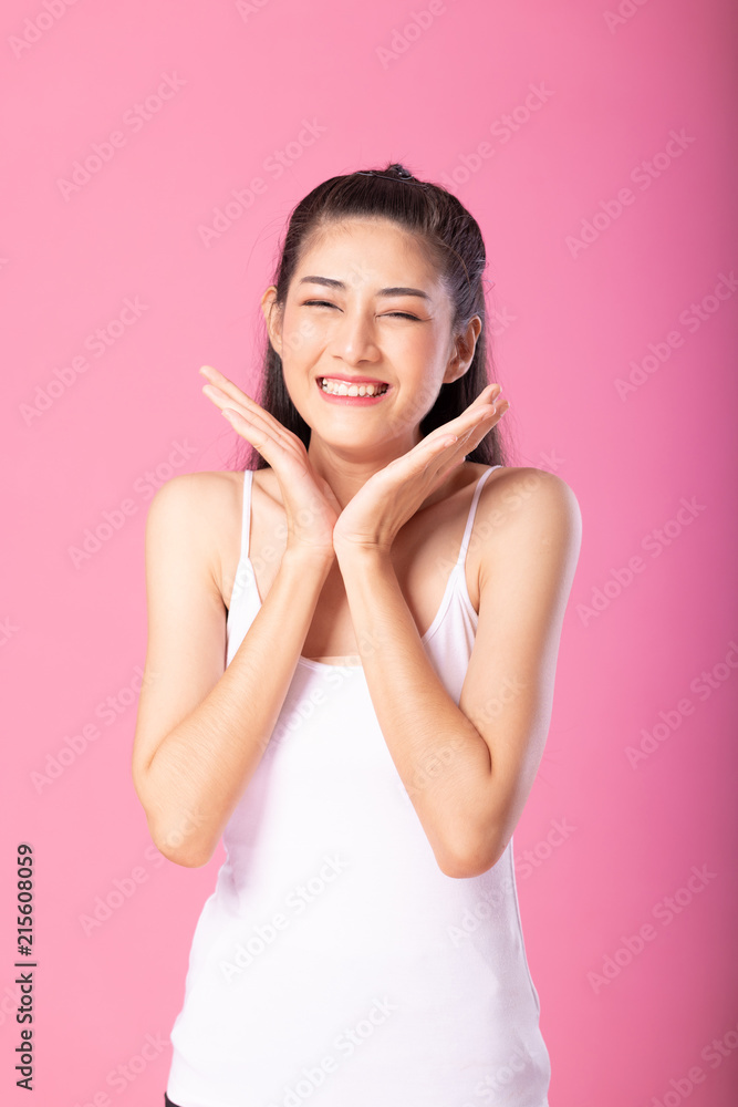 Portrait of a smiling attractive woman in white tanktop outfit with surprise pose while standing and smiling at camera isolated over pink background. Portrait of a smiling attractive woman in white tanktop outfit with surprise pose while standing and smiling at camera isolated over pink background.