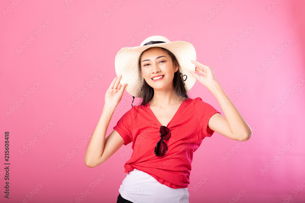 Portrait of a smiling attractive woman in summer outfit and hat posing while standing and looking at camera isolated over pink background. Portrait of a smiling attractive woman in summer outfit and hat posing while standing and looking at camera isolated over pink background.