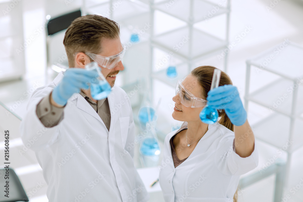 happy scientist and assistant show tube with liquid