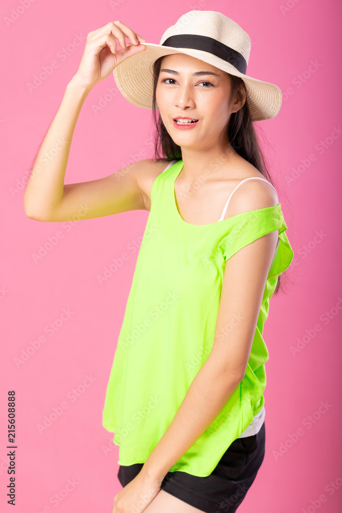 Portrait of a smiling attractive woman in green summer outfit and hat posing while standing and looking at camera isolated over pink background. Portrait of a smiling attractive woman in green summer outfit and hat posing while standing and looking at camera isolated over pink background.