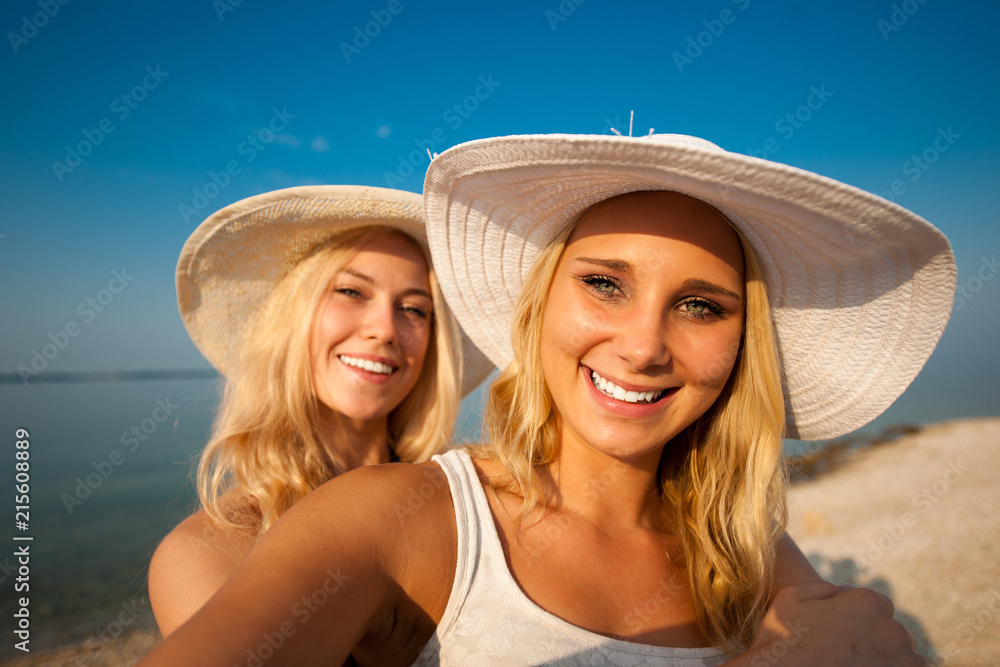 Two young women friends taking selfie on beach