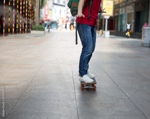 Skateboarder use smartphone sit on skateboard on city street
