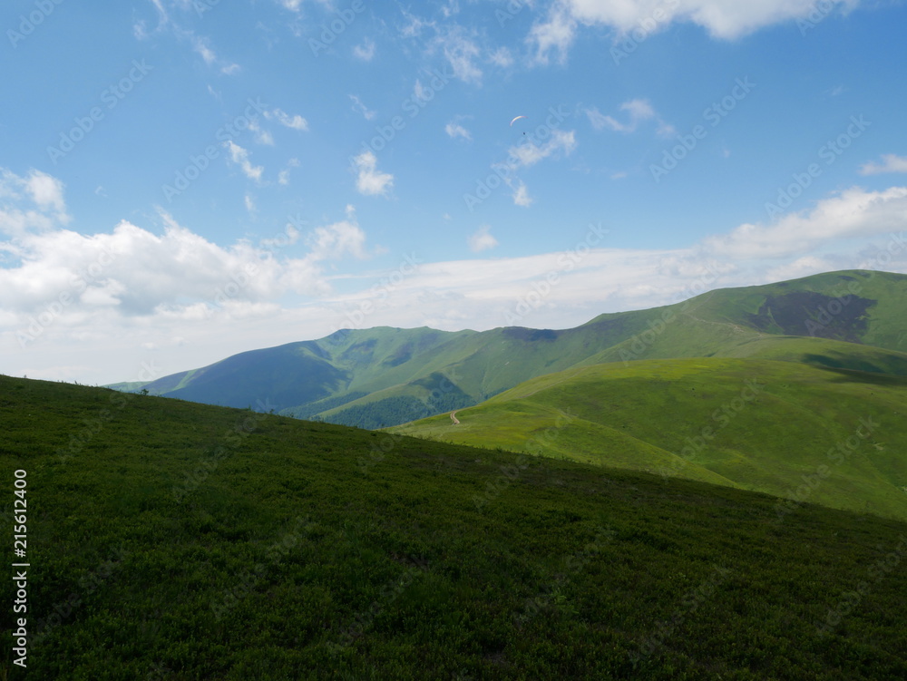 Carpathians / Ukraine - July 07 2017: Paraglider flying parachute in blue sky at a bright sunny summer day. Active lifestyle