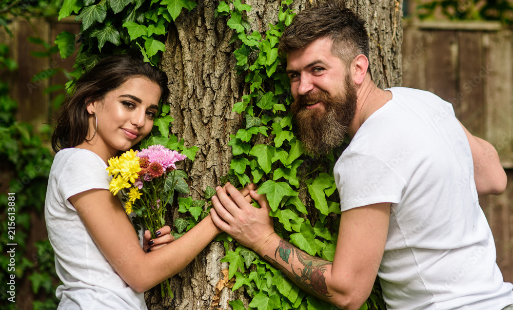Couple in love romantic date walk nature tree background. Pleasant date in nature environment. Man bearded hipster holds hand girlfriend. Couple in love lean on trunk with ivy. United with nature