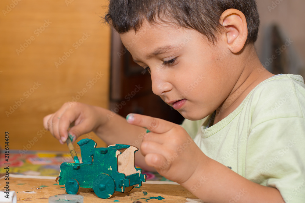 boy is painting a wooden toy car boy is painting a wooden toy car
