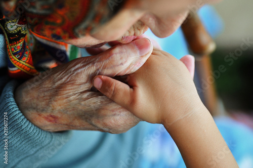 an elderly woman kissing children's hands. Summer walk on the street. 1 year and 90 years.