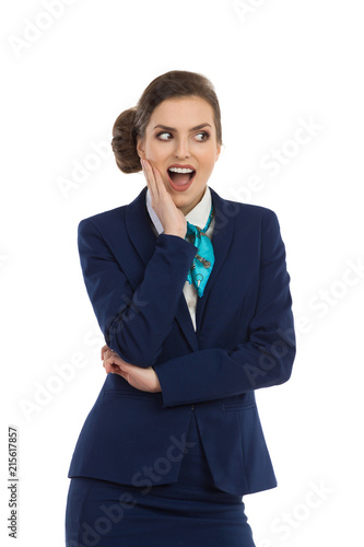 Surprised Woman In Blue Suit And Scarf Holding Hand On Chin And Looking Away