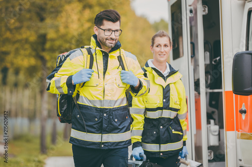 Paramedic nurse and emergency doctor at ambulance with kit