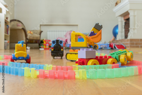 Children's toys on the floor. Close-up. Children's excavator, train and car. The children left behind a mess of toys in the living room.