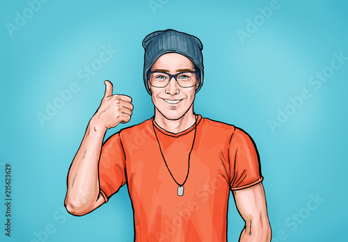 Uśmiechnięty modnisia mężczyzna w szkłach z jak znak. Projekt reklamowy z osobą, która gwarantuje jakość pracy lub usług. Mężczyzna w pomarańczowej koszulce i kapeluszu pokazuje kciuk do góry.