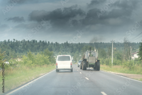 Wallpaper Mural Traktor and white minivan on the rural road under the dark sky wth clouds Torontodigital.ca