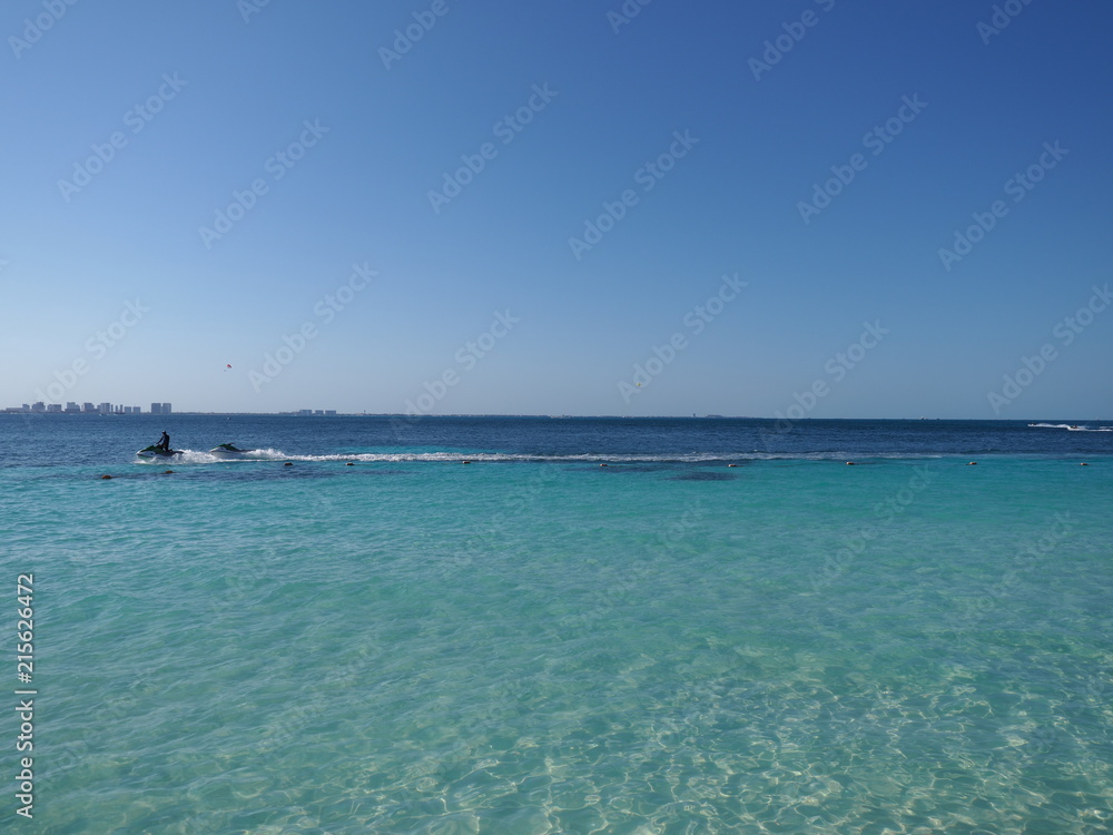View of clean turquoise waters of Caribbean Sea landscape with motor boat and horizon line at Cancun city in Mexico