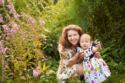 Portrait of happy cheerful mother and daughter in summer garden.