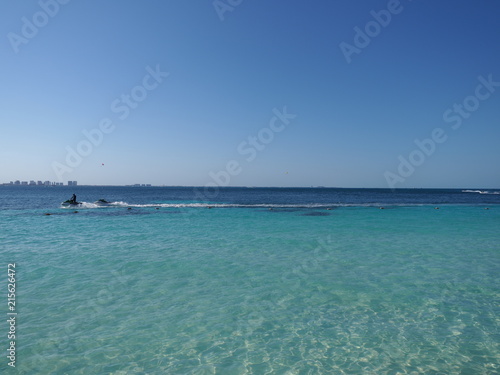 View of clean turquoise waters of Caribbean Sea landscape with motor boat and horizon line at Cancun city in Mexico