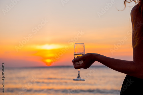 woman at sunset. Girl with glass on background setting sun. romantic date in the evening. girl on the beach. woman on the beach. Elegant girl is drinking champagne. hand with glass 