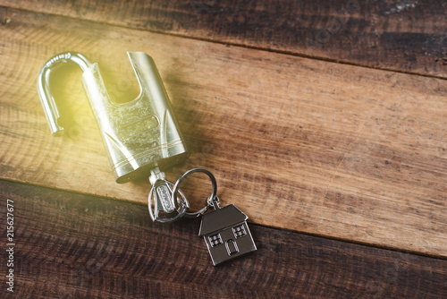 lock, key and house shape key tag on wooden table. house security and privacy concept