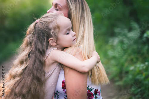 Beautiful young woman and her charming little daughter are hugging photo