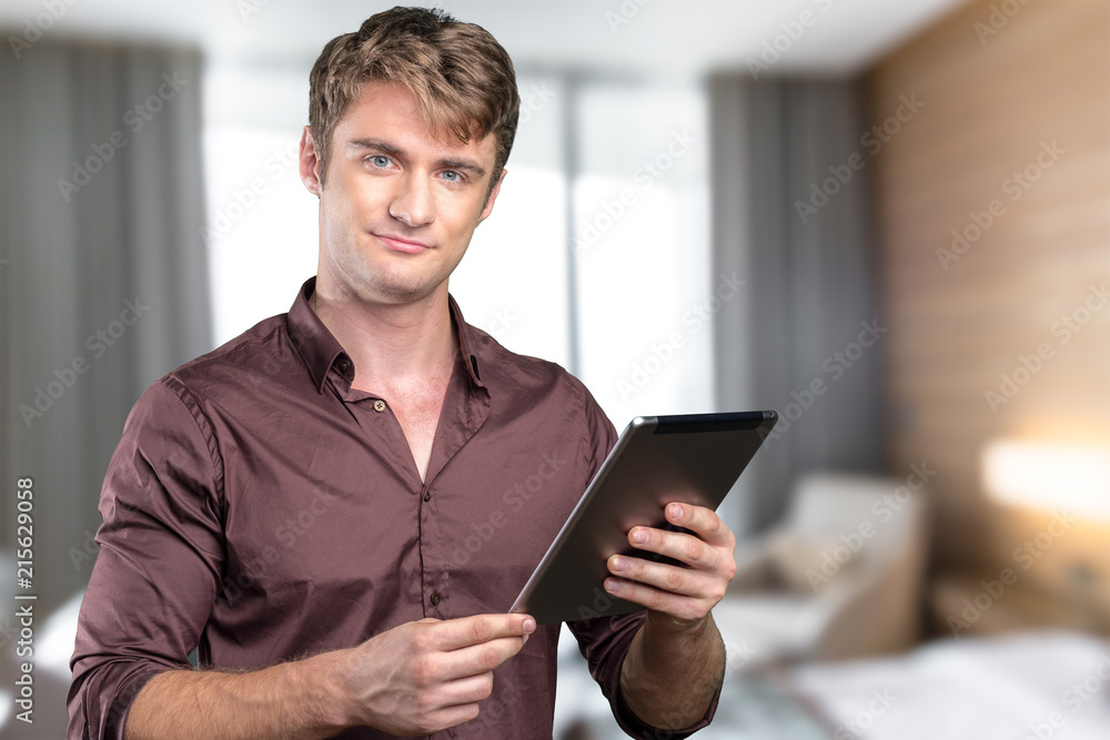 Enjoying time at home. Cheerful young man holding digital tablet Enjoying time at home. Cheerful young man holding digital tablet