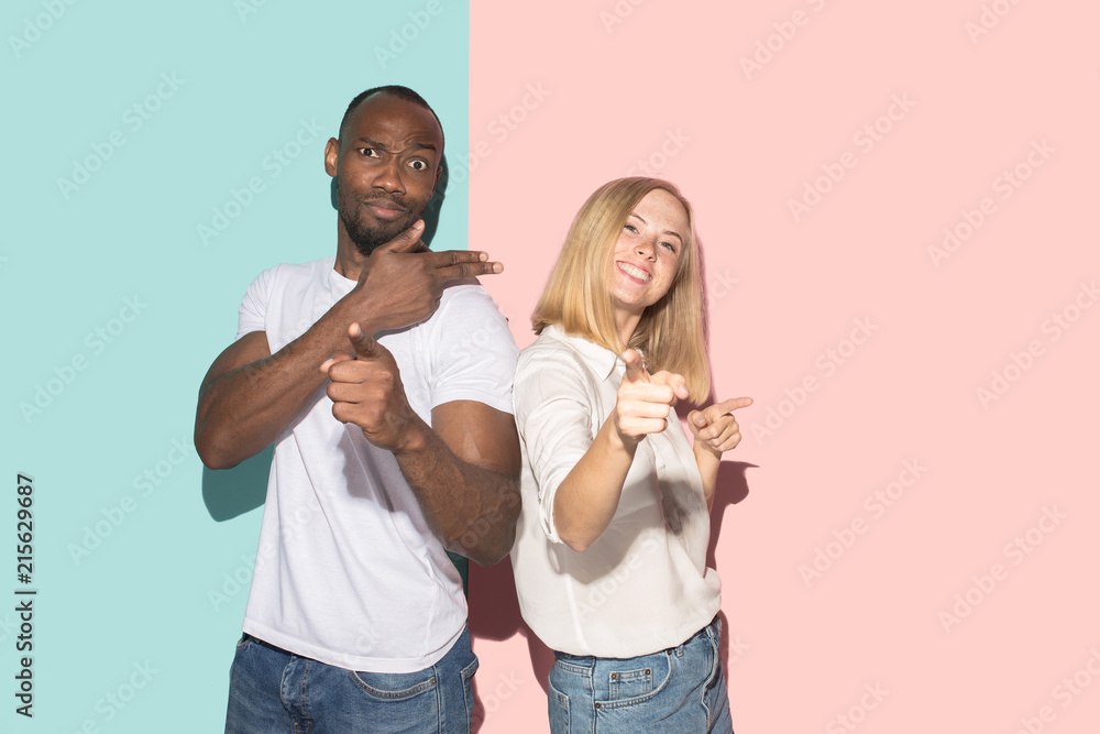 Beautiful female and male portrait on pink and blue studio backgroud. The young emotional couple Beautiful female and male portrait on pink and blue studio backgroud. The young emotional couple
