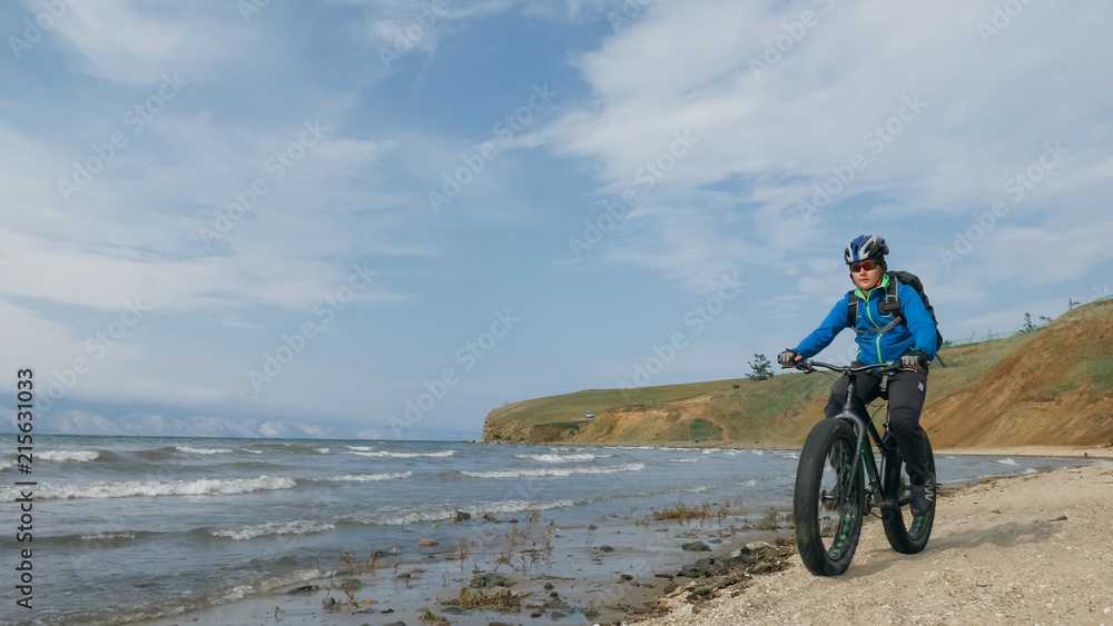 Obraz premium Fat bike also called fatbike or fat-tire bike in summer driving on the beach. The guy is going straight on the beach. On the sand on such a bike ride is not difficult.