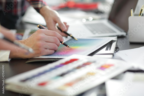 close up.a group of designers discussing the color design of a n